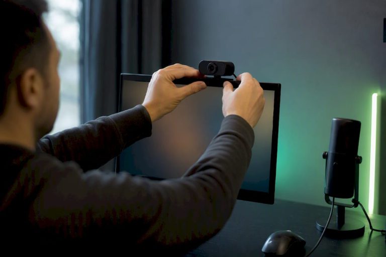 Hands adjusting webcam on monitor