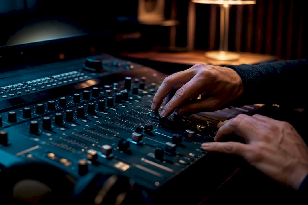 Hands adjusting audio mixer controls